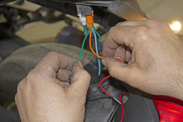 auto mechanic connects the wires in a motorcycle
