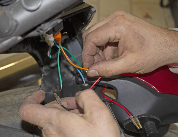 auto mechanic connects the wires in a motorcycle