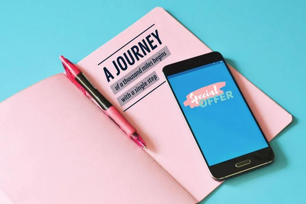Mavi Masa üstünde Smartphone ve pembe defter. Yolculuk planlama