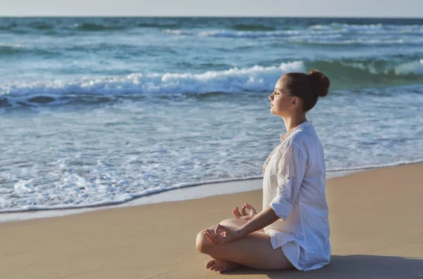 Young woman making meditation on the beach near the sea. — Stock Photo, Image