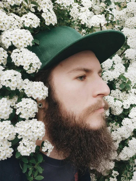 Giovane uomo barbuto vicino all'albero fiorito primaverile — Foto Stock