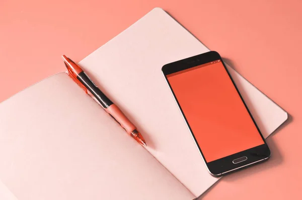 Akıllı telefon ve pembe dizüstü bilgisayar çalışma masasında. Yılın mercan rengi. Tasarım için alay