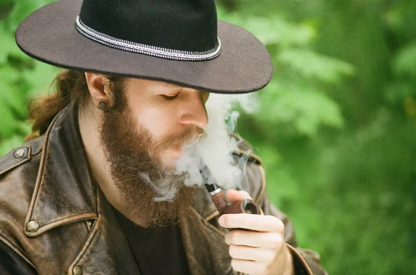 Fotografie de film. Portretul unui bărbat cu barbă în pălărie fumând ţeavă de tutun . — Fotografie, imagine de stoc