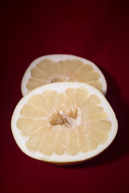 Kırmızı bir arka plan üzerinde olgunlaşmış pomelo iki yarısı