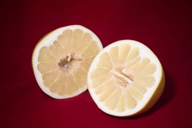 Kırmızı bir arka plan üzerinde olgunlaşmış pomelo iki yarısı