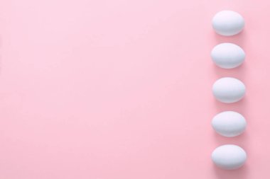 Pembe arka planda bir satırda Paskalya yumurtaları. Paskalya yaratıcı tebrik kartı. Düz yatıyordu. Boşluk Kopyala. Üst görünüm