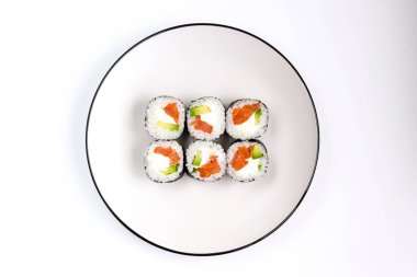 Beyaz tabakta avokado, kırmızı balık somon ve whit peynirfila ile taze hazırlanmış suşi rulo. Üstte görüntü