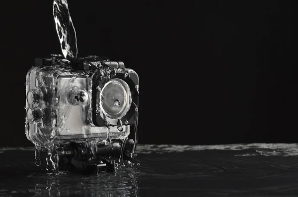 Flowing water on the waterproof action camera on wet black stone background