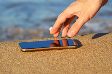 İnsan eli su geçirmez akıllı telefon kum üzerine alarak