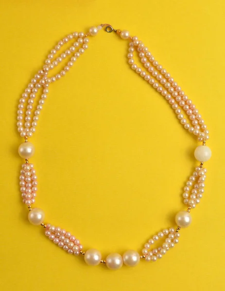 Pearl necklace on yellow background