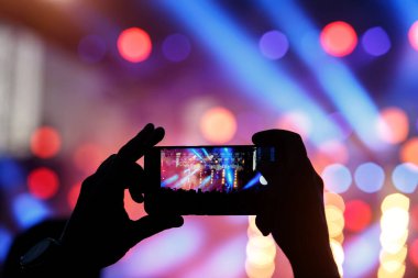 Genç adamın silueti, cep telefonunda fotoğraf rock konseri, açık hava festivali.