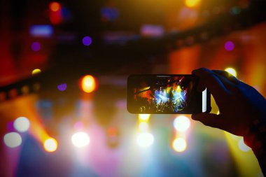 Gençler akıllı telefondan bir konserin fotoğrafını veya videosunu çekiyor.