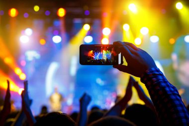 Konserde kalabalıktaki bir adam sosyal medyada yayınlanmış akıllı bir telefondan video kaydı ve resimler yapıyor.