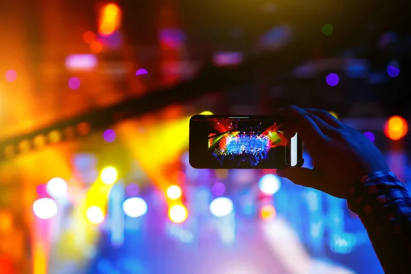 Young people shoot photo or video of a concert on smartphone.