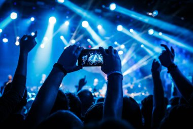 Fan konserde cep telefonuyla fotoğraf çekiyor.