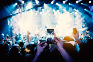 El kameralı akıllı telefon bir konseri filme çekiyor.