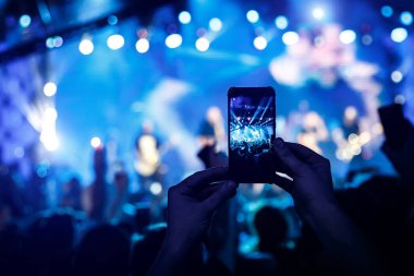 El kameralı akıllı telefon bir konseri filme çekiyor.