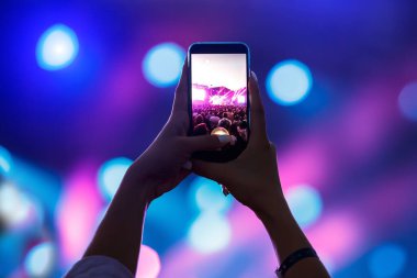 Cep telefonlu bir konser kaydı, akıllı telefonlu eller silueti.