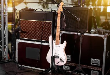 Amplifikatörler ve diğer müzik ekipmanları arasında beyaz gitar sahnede