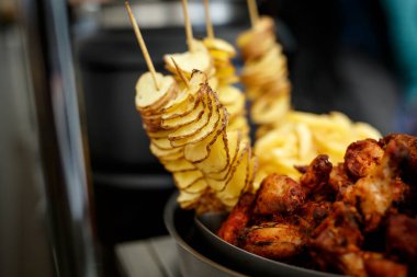 Ev yapımı organik kızartılmış ince patates cipsi. Arka planda tavuk kanatları. Bira için atıştırmalıklar