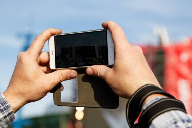 Akıllı telefonları elinde tutan ve fotoğraf çeken bir adam. Yazın açık hava müzik festivalinde fotoğraf çekiliyor..
