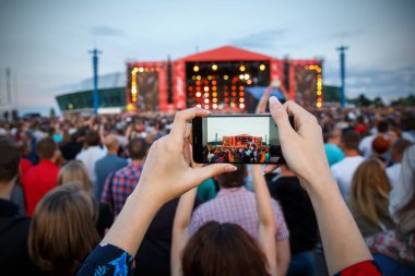 Akıllı telefon kayıtları olan bir kızın elleri yaz festivalinde, alacakaranlık vakti