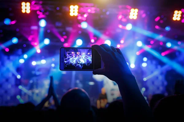 Fan konserde cep telefonuyla fotoğraf çekiyor.