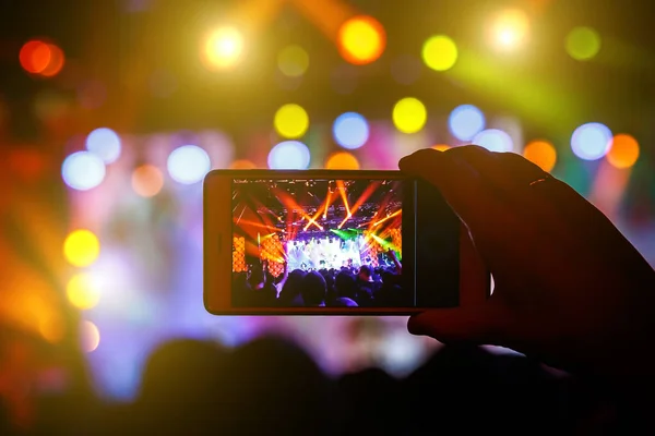 Fan taking photo of concert at festival by smatphone