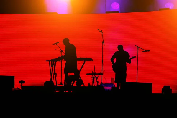舞台上摇滚乐团音乐家 吉他手和红色背景键盘手的轮廓 — 图库照片