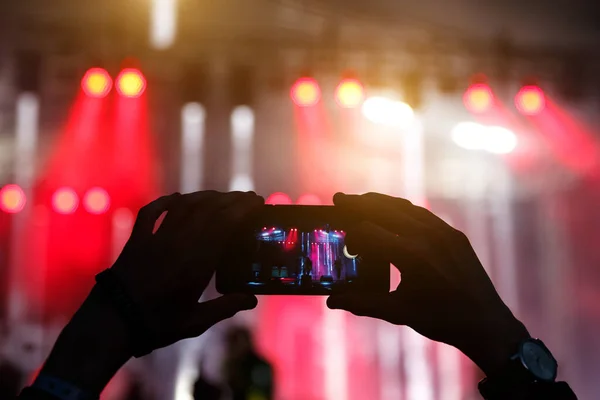 silhouette of hands with a smartphone at a big music festival, video recording