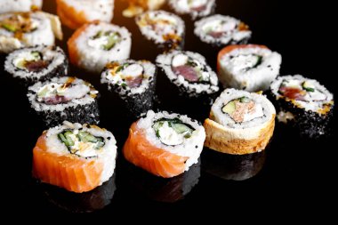 Japon suşisi siyah zemin üzerinde yuvarlanıyor, yan görünüm