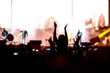 Konserdeki bir kızın silueti, şovun zevki. Kaldırın ellerinizi
