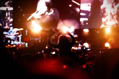 Konserdeki bir kızın silueti, şovun zevki. Kaldırın ellerinizi