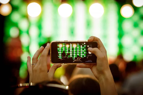 Mobile phone in hand during the shooting of a concert, light show