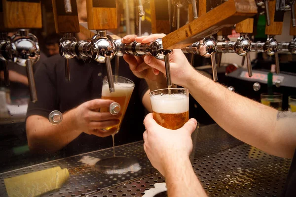 Bartender, Barman hand at beer tap pouring draught craft beer