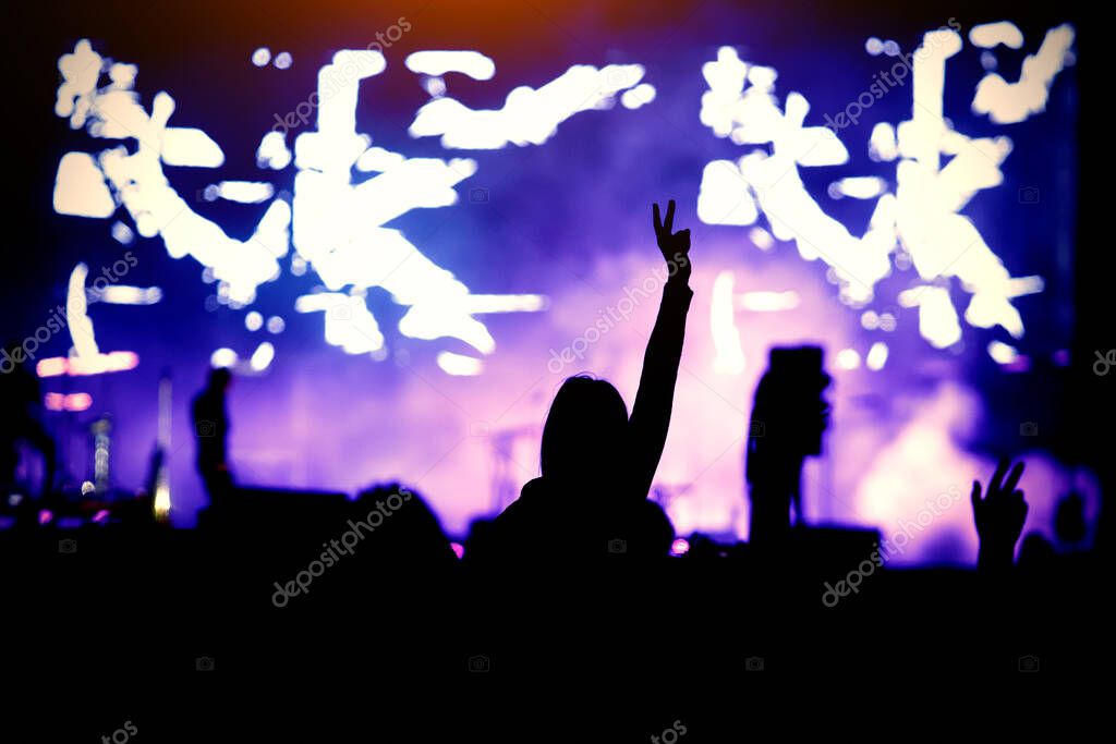 Silhouette of a girl at a concert, the pleasure of the show. Raised hands