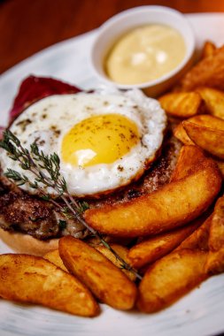 Çırpılmış yumurtalı biftek ve beyaz tabakta kızarmış patates. Yan görüş. Menüde bir kafe, bir restoran var.
