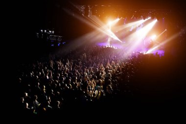 En sevdikleri grubun konserinde ellerini kaldıran insanlar. Kalabalık bir gösteri izliyor.