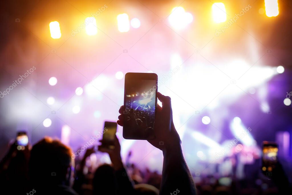 Hand with a smartphone records live music festival, live concert, live concert