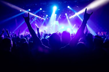 Müzik konserinde elini kaldırmış bir adamın silueti..