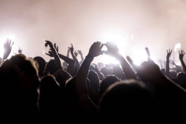 Elleri havada ve akıllı telefonlardan oluşan kalabalık bir konser kaydediyor.