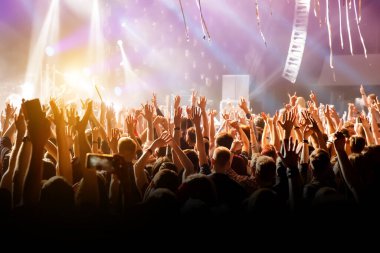 En sevdiği grubun konserinde elleri havada bir adam. Sahneden gelen ışık