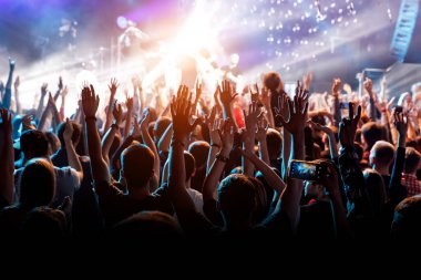 En sevdiği grubun konserinde elleri havada bir adam. Sahneden gelen ışık