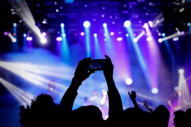 Cep telefonu kamerasıyla bir konser çekiyoruz, sahnenin mavi ışığı.