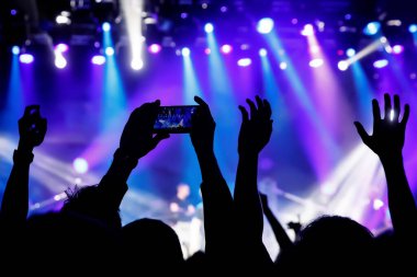 Cep telefonu kamerasıyla bir konser çekiyoruz, sahnenin mavi ışığı.
