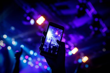 Cep telefonu kamerasıyla bir konser çekiyoruz, sahnenin mavi ışığı.