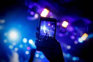 Cep telefonu kamerasıyla bir konser çekiyoruz, sahnenin mavi ışığı.