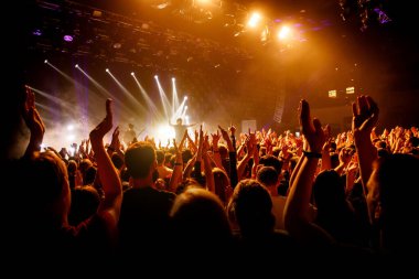 Crowd on music show, happy people with raised hands. Orange stage light clipart