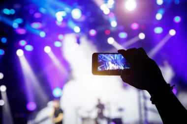 Cep telefonu kamerasıyla bir konser çekiyoruz, sahnenin mavi ışığı.