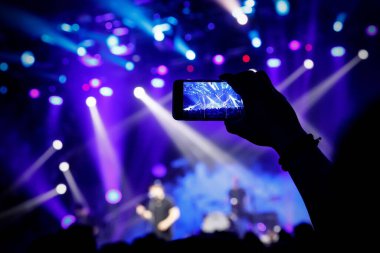 Cep telefonu kamerasıyla bir konser çekiyoruz, sahnenin mavi ışığı.